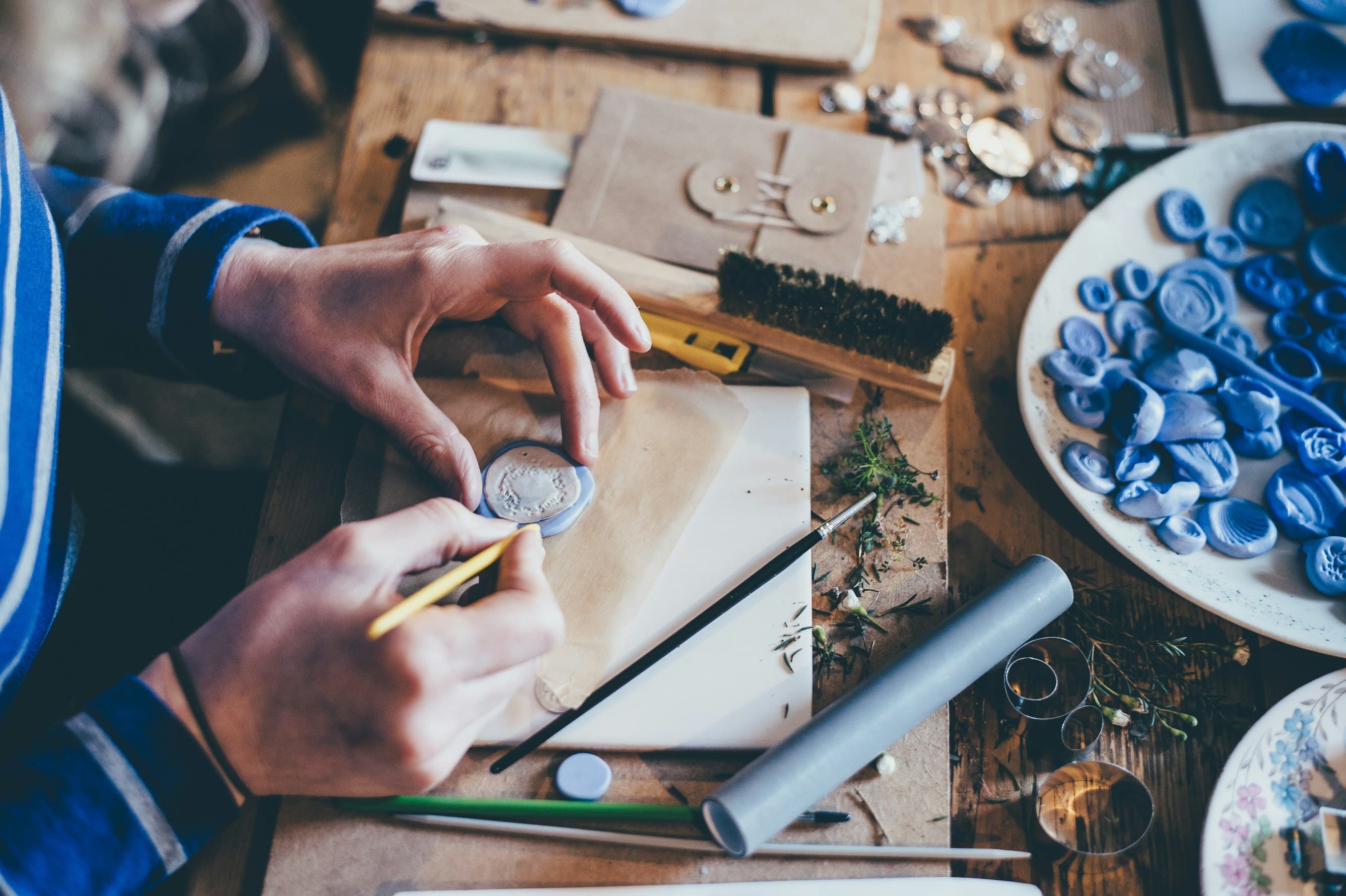 A maker at a bench, working on a piece surrounded by tools and materials